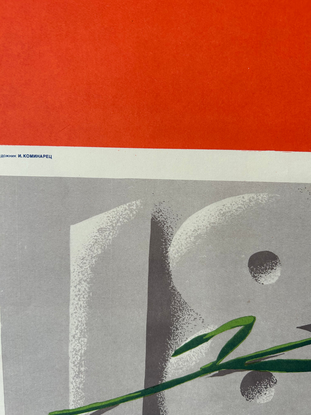 A close-up of a graphic art print featuring a bold red-orange block at the top, a white horizontal band with small blue text, and a gray typographic design with green leaves in the foreground.