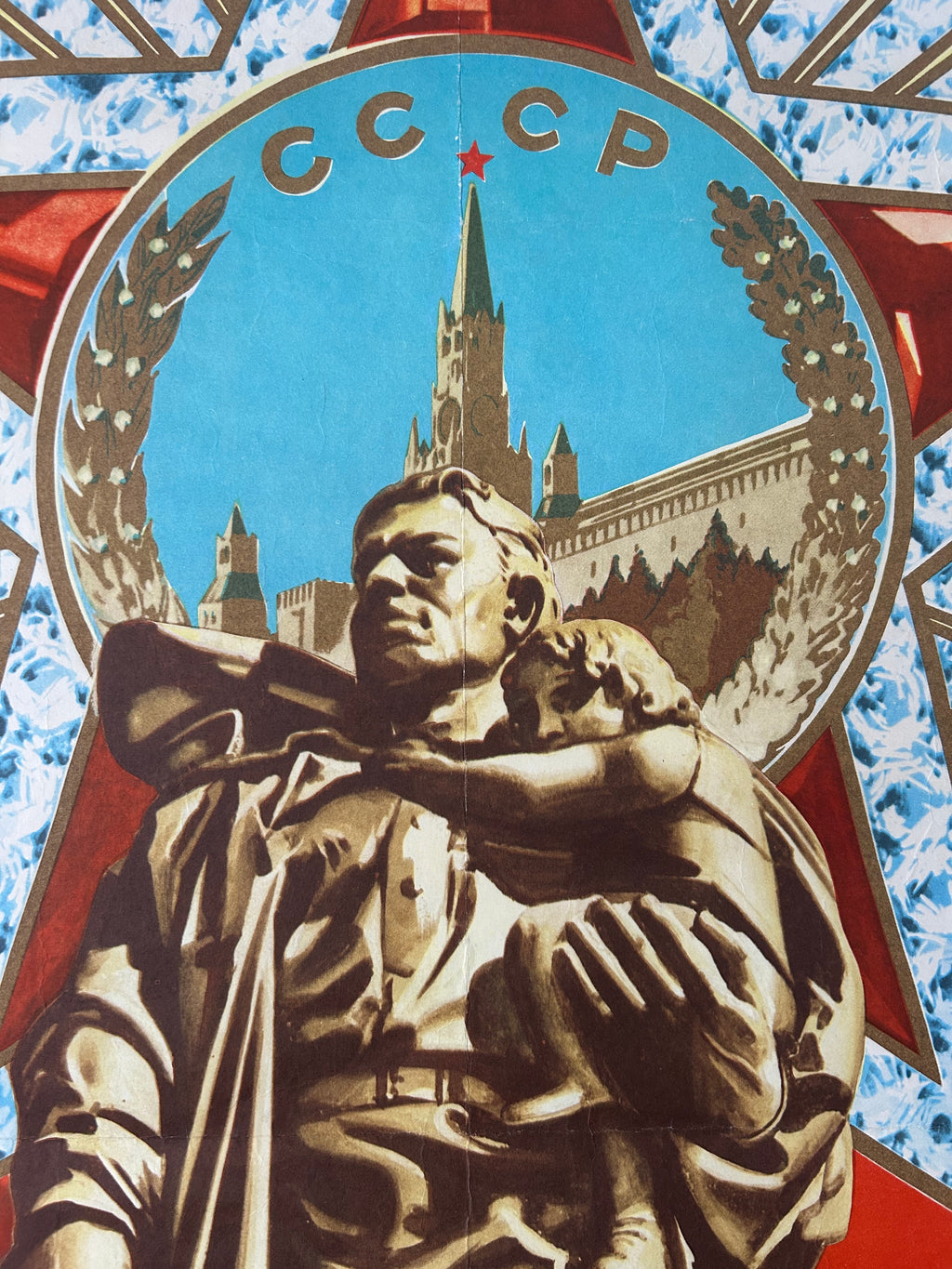 A Soviet-themed artwork or poster featuring a bronze-toned statue of a soldier holding a child in the foreground, with a large red star and circular emblem behind showing the text “УССИЯ СОНИЯ” above a cityscape and blue sky.