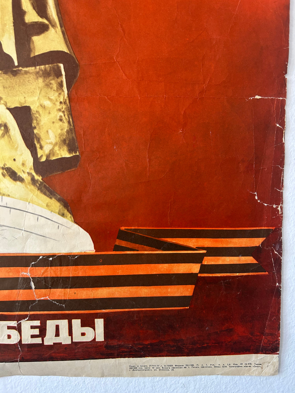 A vintage Soviet propaganda poster featuring a large gold hammer and sickle on the left, a red background, black and orange striped steps, and white Cyrillic text at the bottom. The poster shows visible aging, creases, and wear marks.