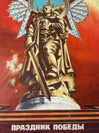 A vintage Soviet-style poster featuring a large golden statue of a soldier holding a sword, set against a vivid red background with a blue sky and white Cyrillic text at the bottom reading 'Prazdnik Pobeedy'.