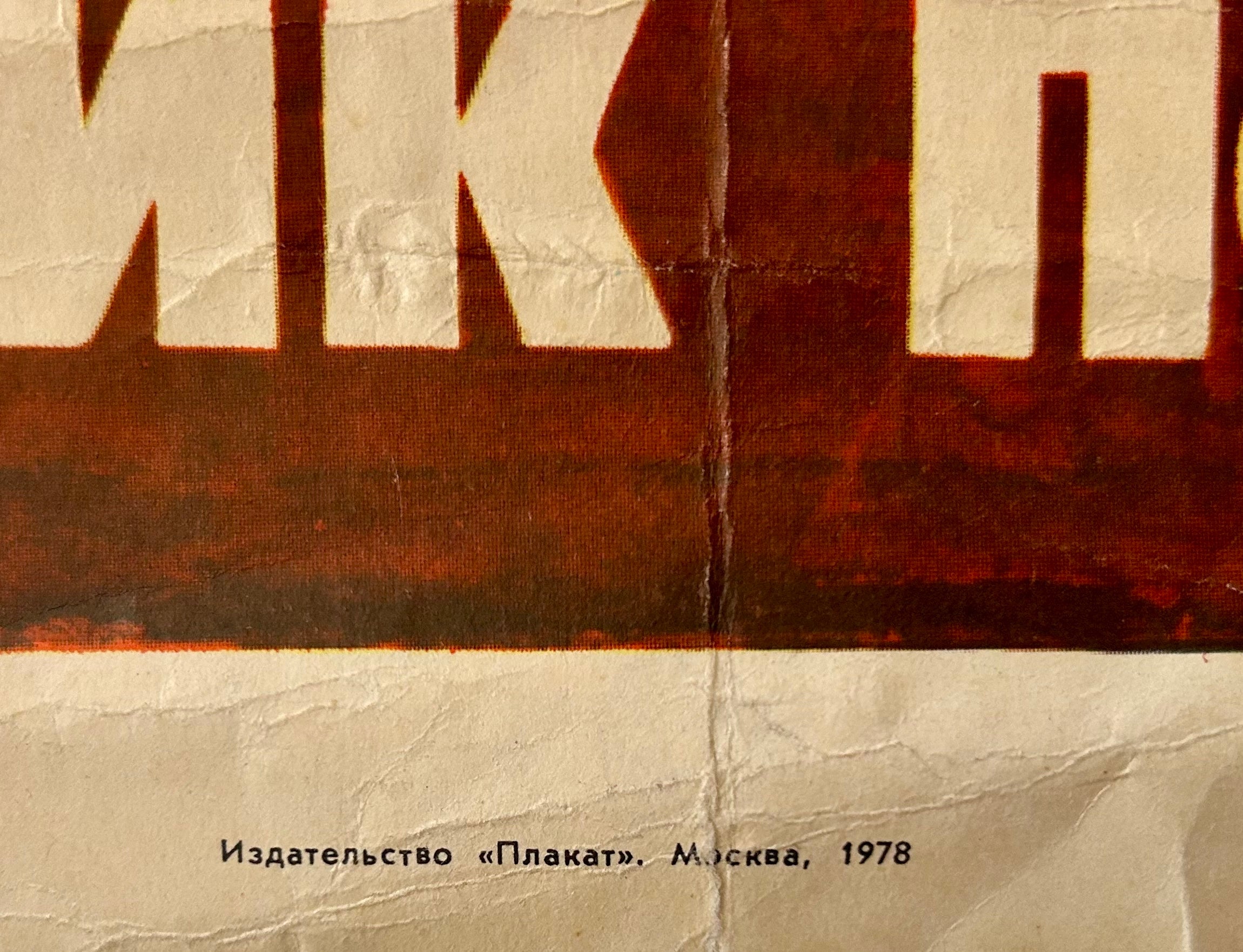 Close-up of a vintage Russian poster print with bold cream Cyrillic lettering over a dark reddish-brown block, printed on aged off-white paper with visible creases and fold lines. Small black text at the bottom reads 'Издательство “Плакат” Москва 1978'.