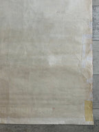 A large sheet of textured, off-white to beige parchment paper or aged craft vinyl, secured with tape on the right and bottom edges against a gray wood background.
