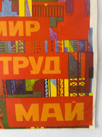 A close-up of a vintage Soviet propaganda poster featuring bold yellow Cyrillic text reading 'МИР ТРУД МАЙ' on a red background with an abstract architectural collage.