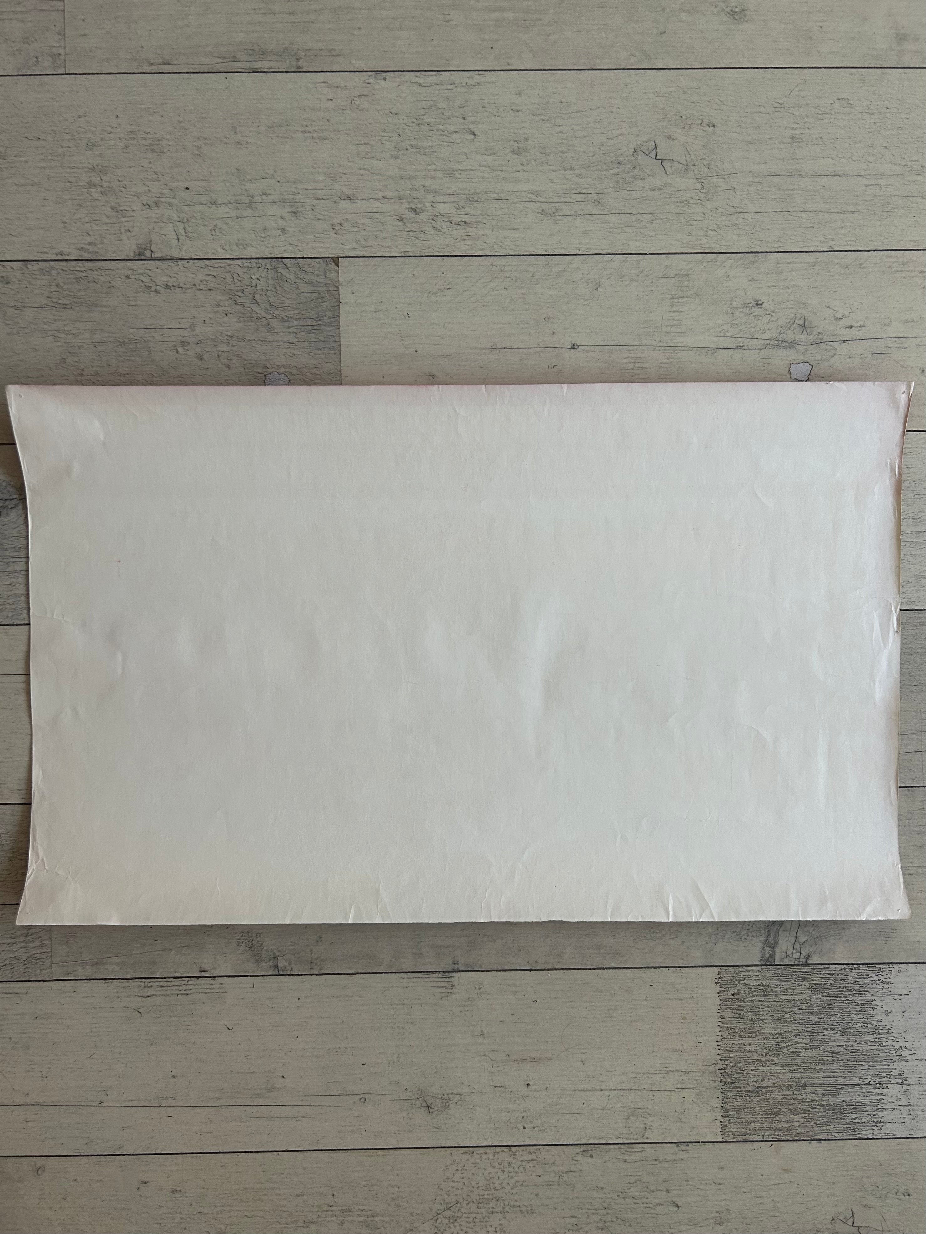 A blank, off-white rectangular pillow sham or pillow cover laid flat on a light gray wood plank floor.