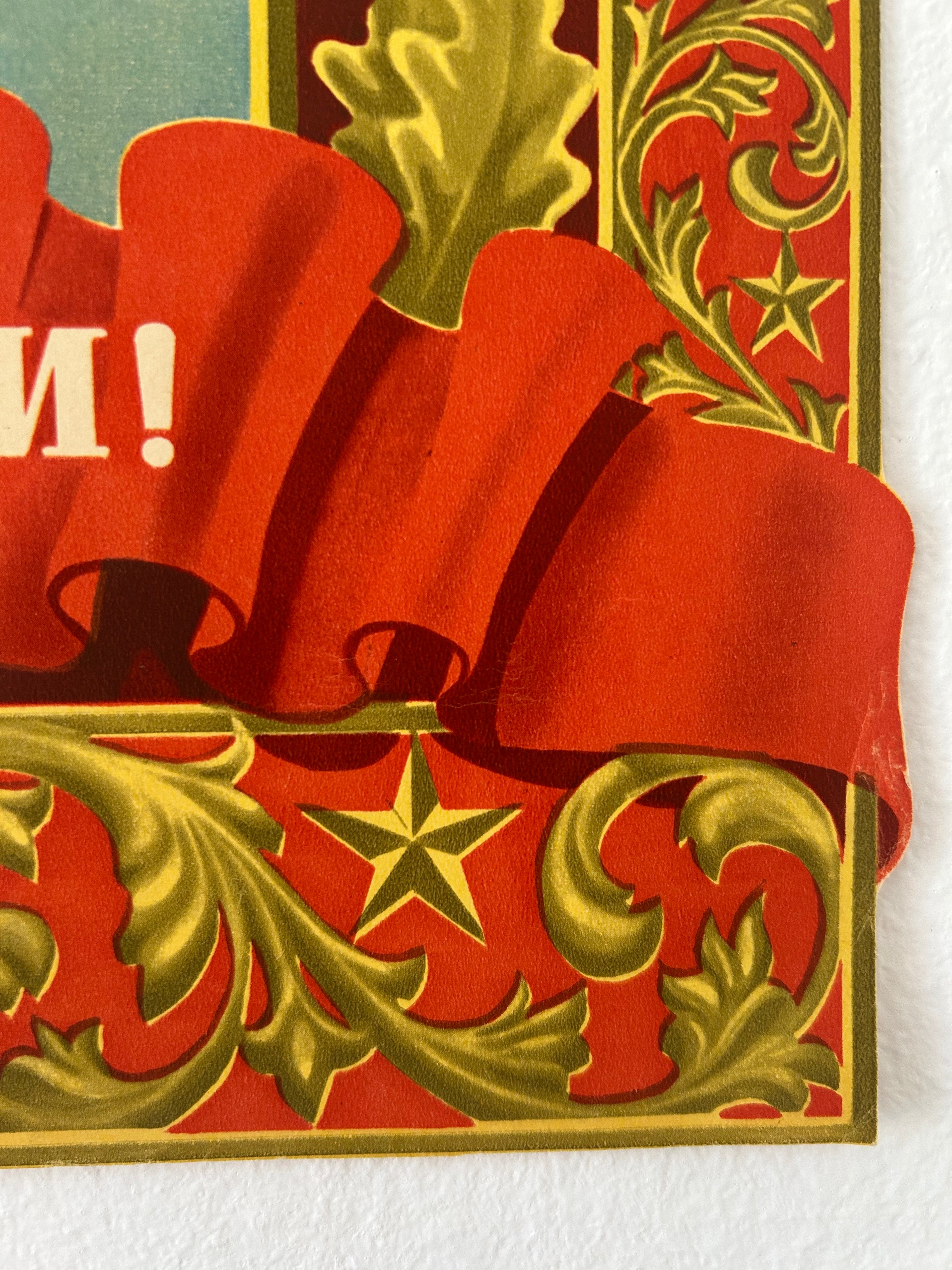A close-up of a red and gold Christmas-themed decorative card or gift packaging design, featuring a large red bow, ornate gold scrollwork, a gold star, and partial white text on a red background.