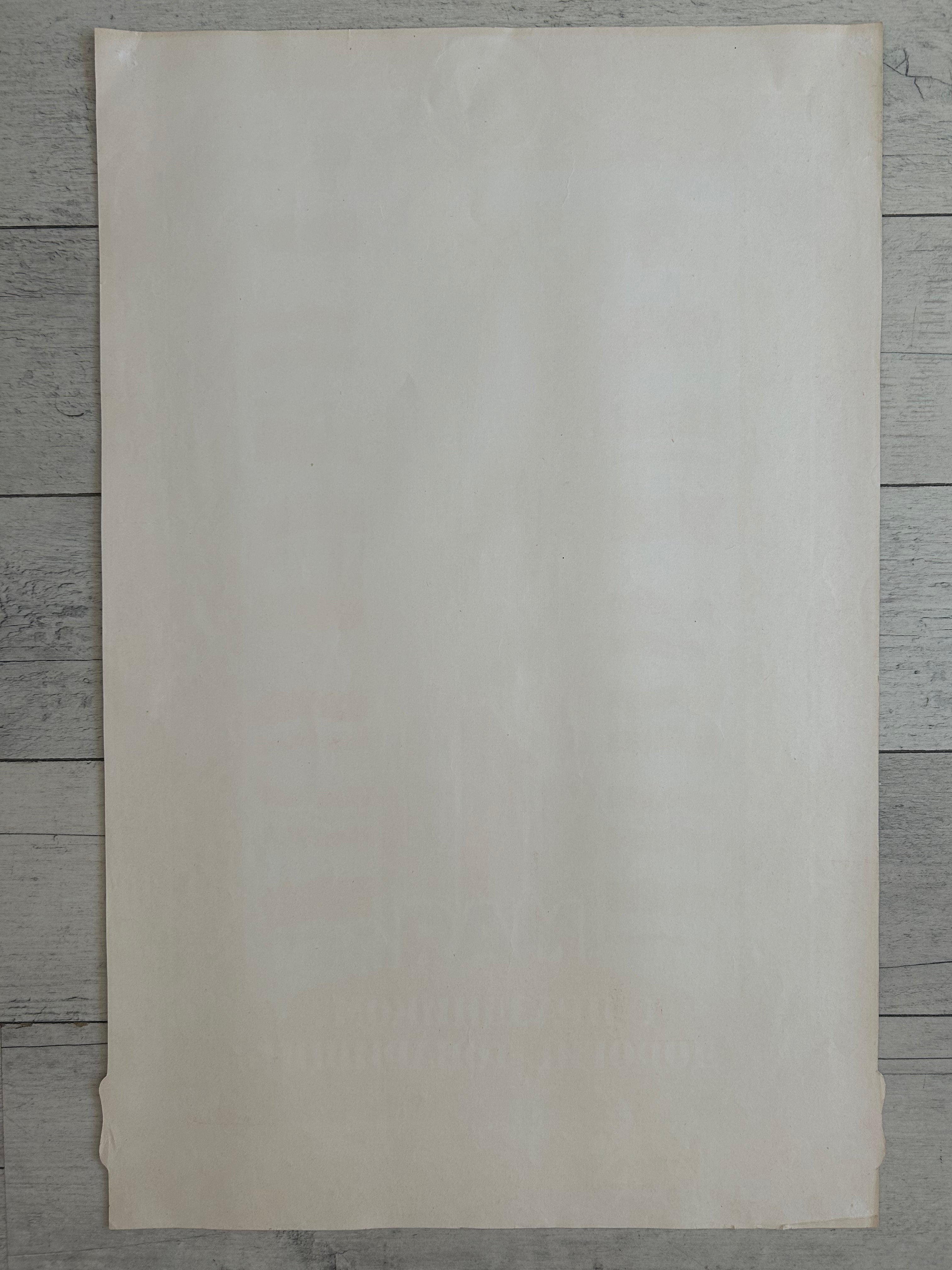 A blank, off-white textured paper sheet or card with slightly warm cream tones, laid flat on a gray wood plank background.