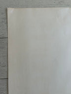 A blank, off-white sheet of paper or cardstock standing vertically on a gray wooden plank surface.