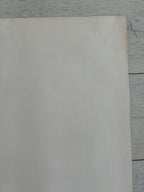 A blank, off-white sheet of paper or cardstock with slight warm yellowing, placed on a light gray wood-grain surface.