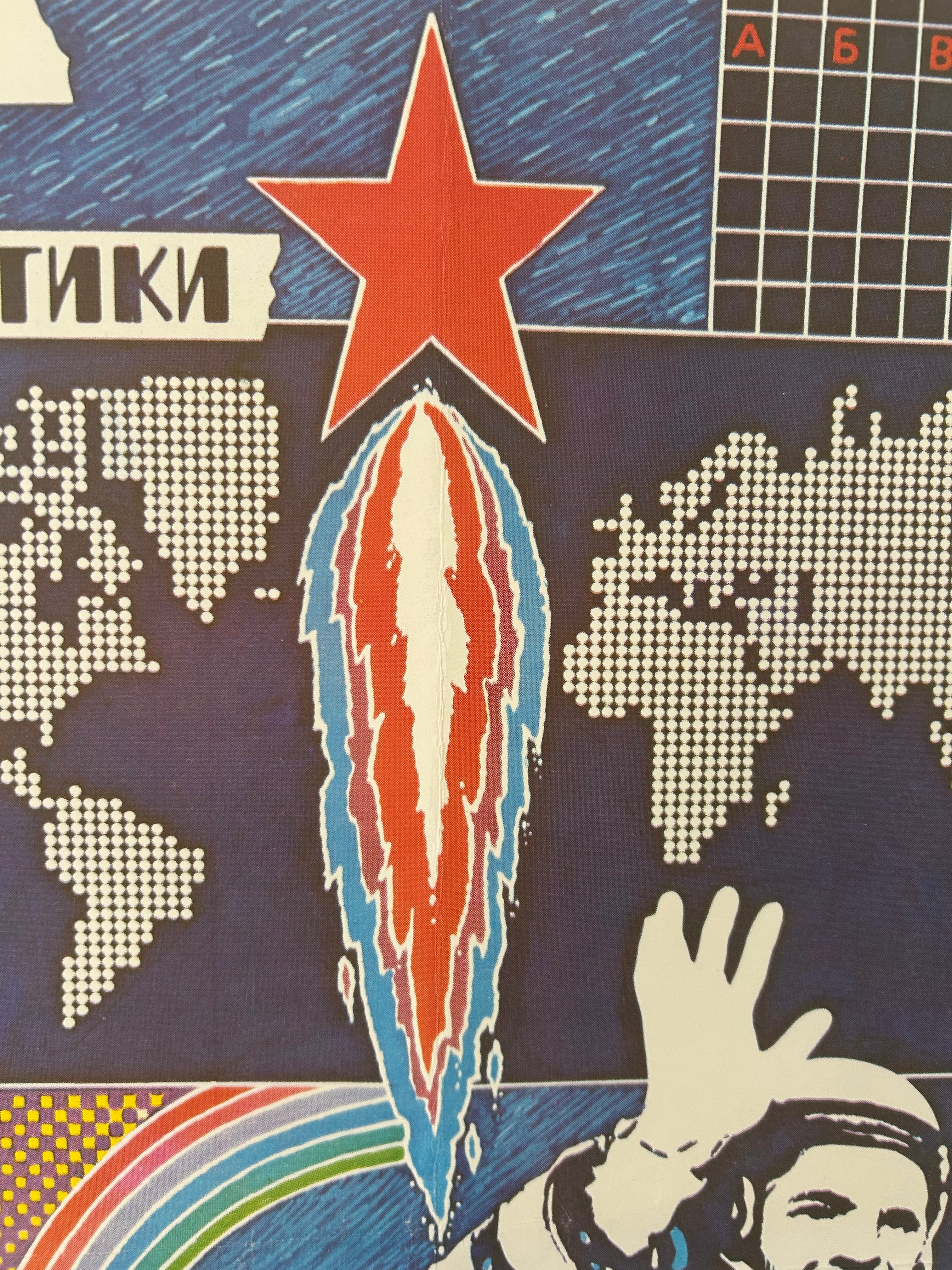 A close-up of a graphic print or textile featuring a red star, a pixelated world map, a rocket trail, and a stylized astronaut waving, with partial Cyrillic text visible.
