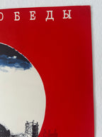 A close-up of a red poster or print featuring white Cyrillic text at the top, a large white circular shape with dark blue sky and black architectural illustration inside, and part of a white wall visible around the edges.