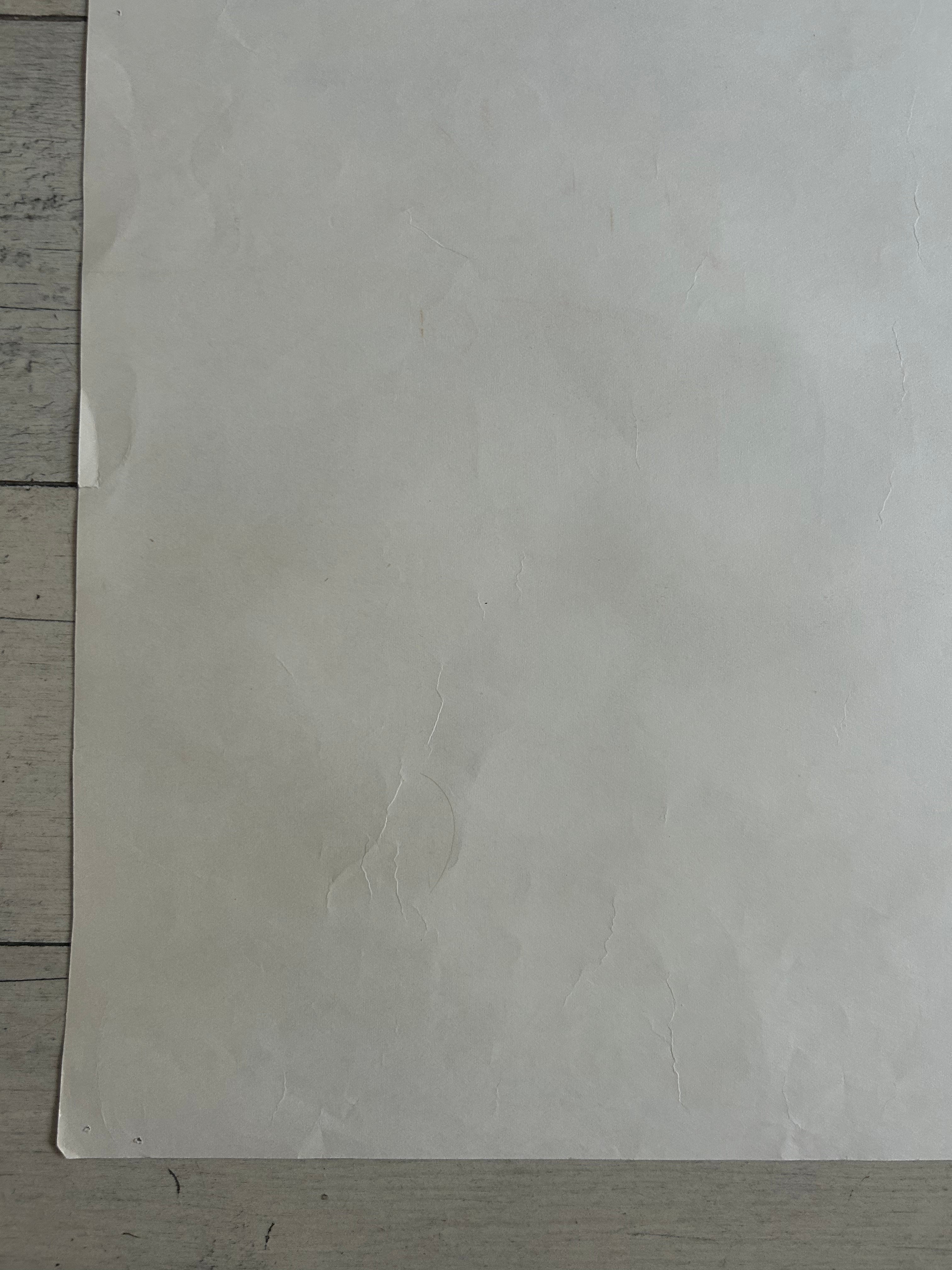 A large, slightly textured off-white sheet of paper or cardstock laid flat on a light gray wooden surface.