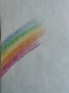 A rainbow-colored dotted pattern, likely a crayon or pastel pencil swatch, on a textured off-white paper background.