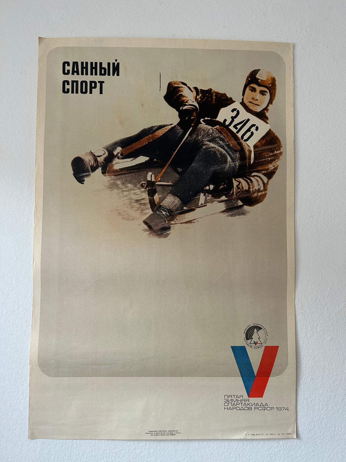 A vintage Soviet sports poster for winter sports, featuring a skater in action with the text 'СТКАННО СЛОВО' at the top and a stylized red and blue 'V' logo at the bottom, displayed against a light gray wall.