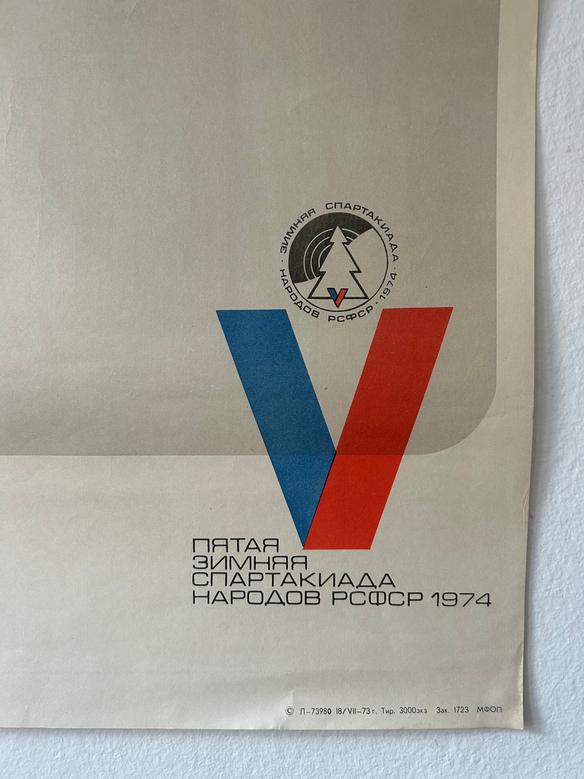 A vintage Soviet winter sports poster or booklet cover from 1974, featuring a large stylized letter 'V' in blue and red, with Cyrillic text and a circular emblem near the top, photographed against a white textured background.