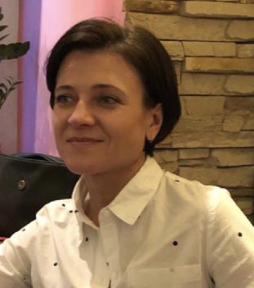 Woman wearing a white shirt with black polka dots in front of a stone wall.